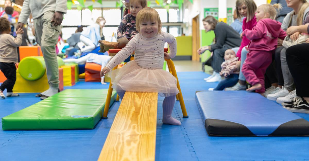 A toddler navigates the balance beam in the soft play area at Babyzone Croydon. Photo credit. Babyzone.
