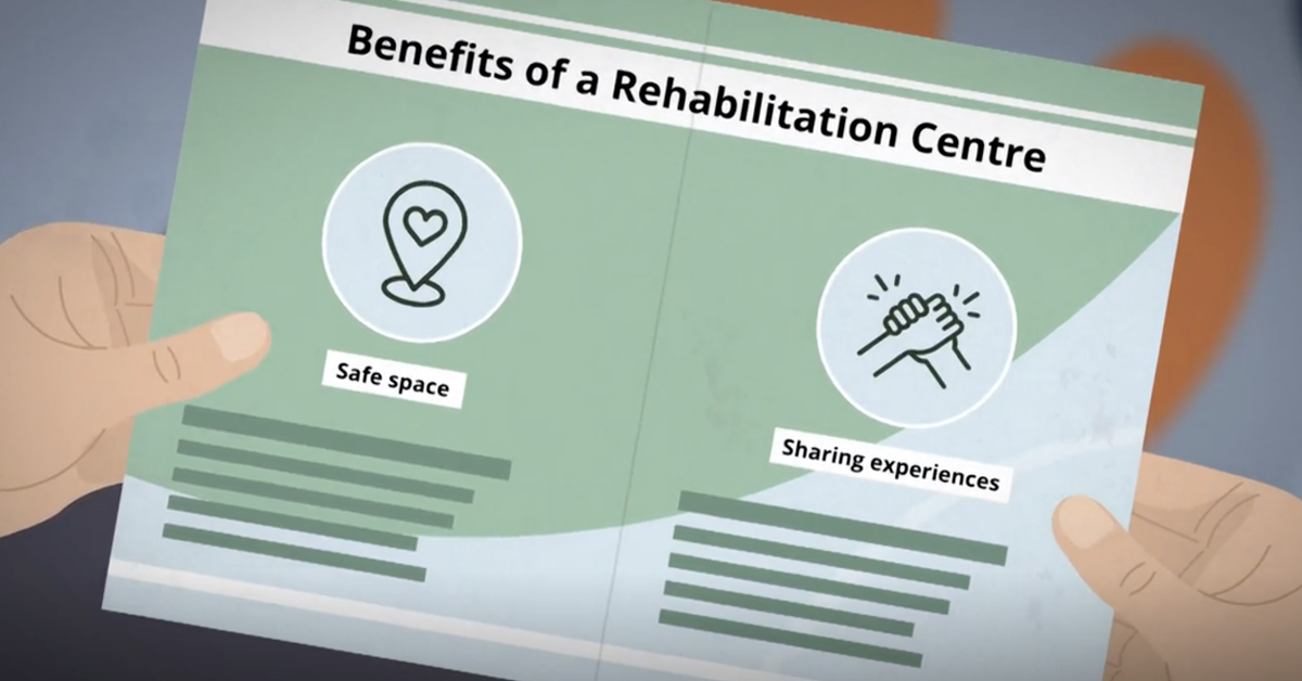 A person in custody reads a pamphlet. The text reads: 'Benefits of a Rehabilitation Centre', followed by 'Safe space' and 'Sharing experiences'.