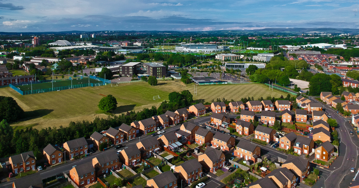Aerial view of Greater Manchester, featuring a housing estate with playing fields and stadiums.