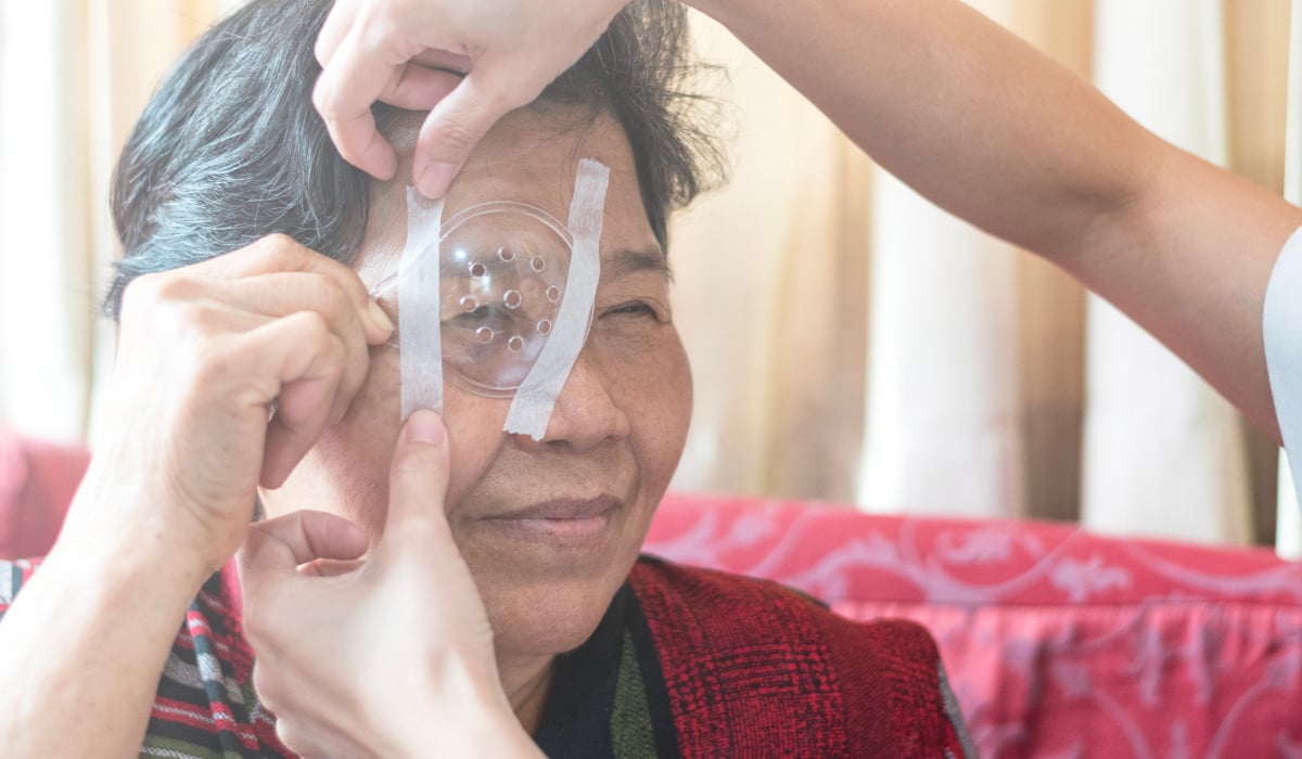 A patient being fitted with a clear eye protector after cataract surgery.