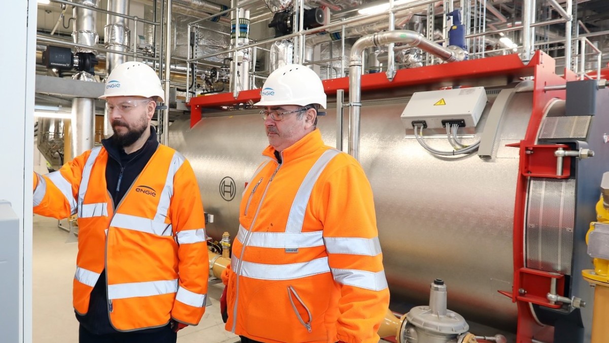 Two men in orange reflective vests and white hard hats inspect part of the innovation district at Newcastle Helix.