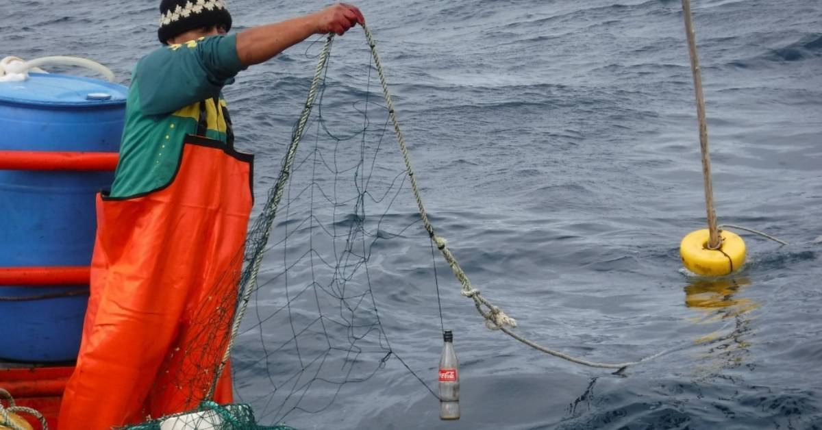 image shows fisherman using glass bottles to deter dolphins from his fishing nets