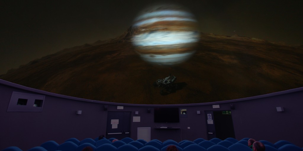 A large screen that's showing the planet Jupiter in space