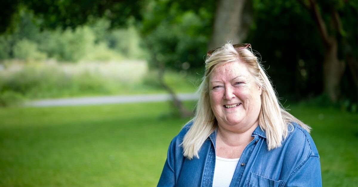 Elizabeth smiling surrounded by greenery in a park