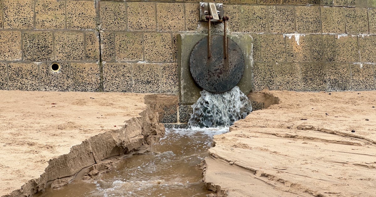 Storm overflow pipe releasing wastewater on to beach