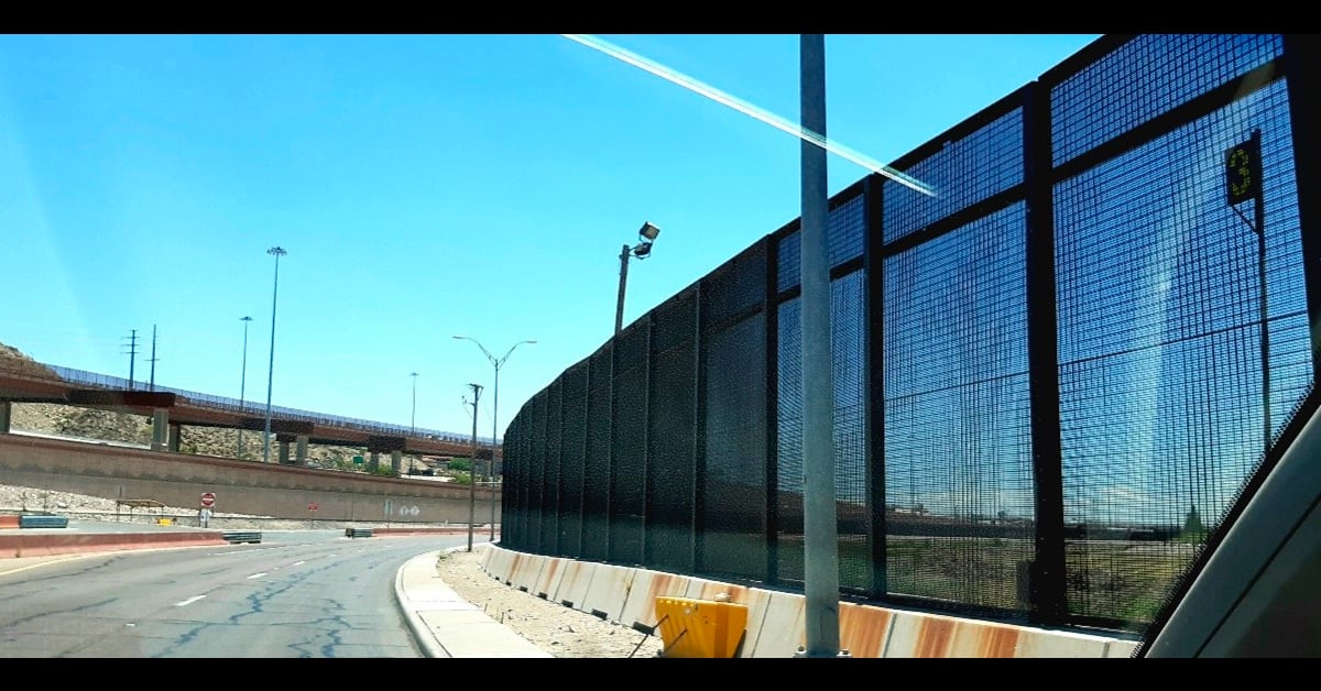 A line of fencing along the road near the US-Mexico border.