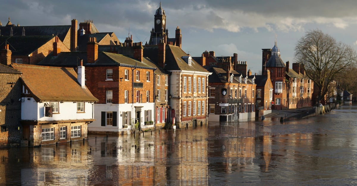 Buildings and riverside businesses stand in a flooded street as the River Ouse bursts its banks in York, England.