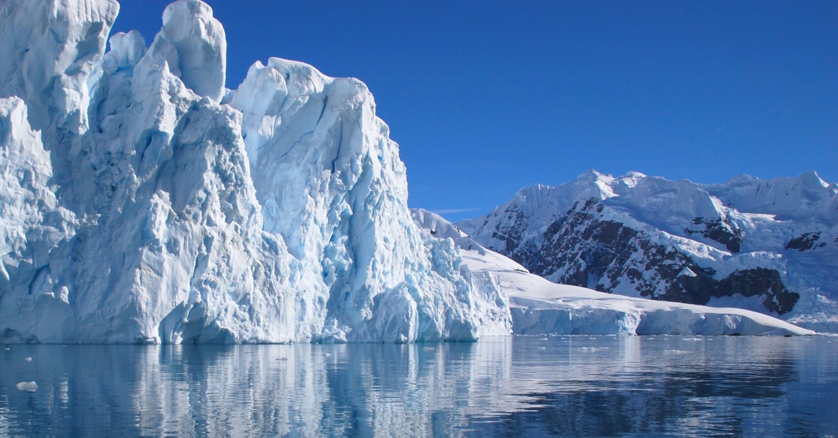 A partially submerged glacier set against a blue sky.
