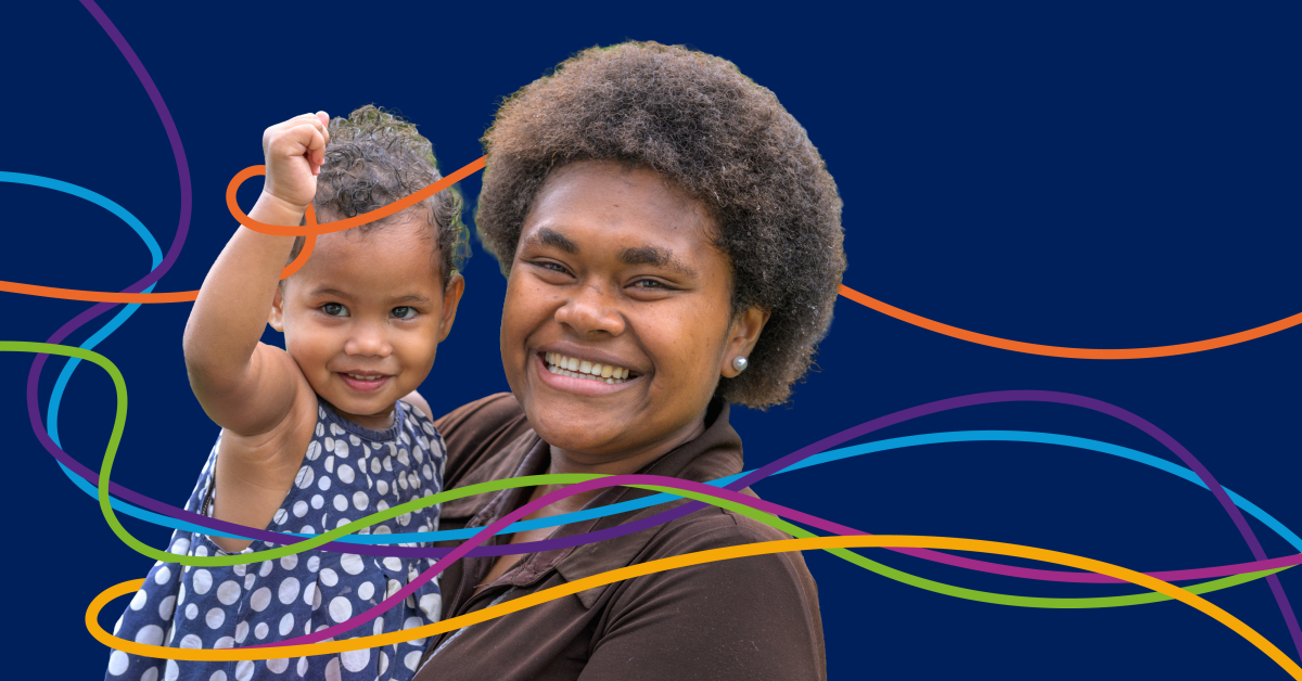 A mother holding her child smiles towards the camera against a navy blue background with colourful ribbons. Image by World Health Organization.
