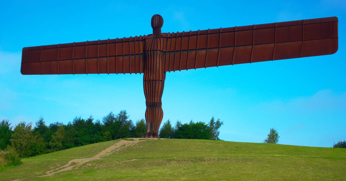Angel_of_the_North_statue_on_grassy_hill_with_blue_sky_background