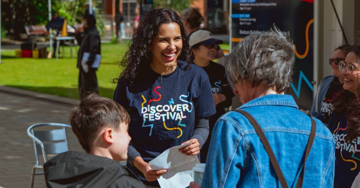 Image shows a student ambassador welcoming families to discover festival