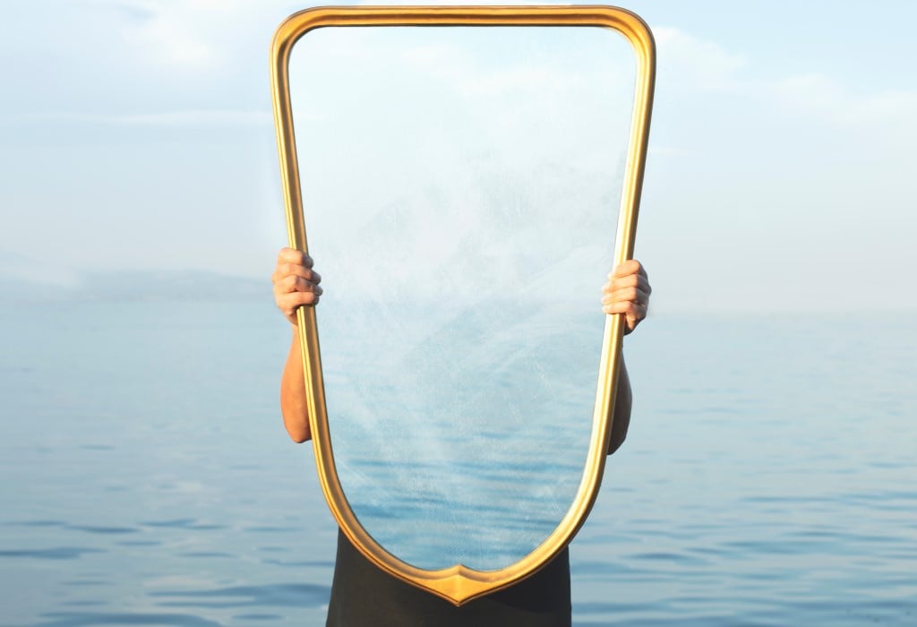 Person holding mirror reflecting sea