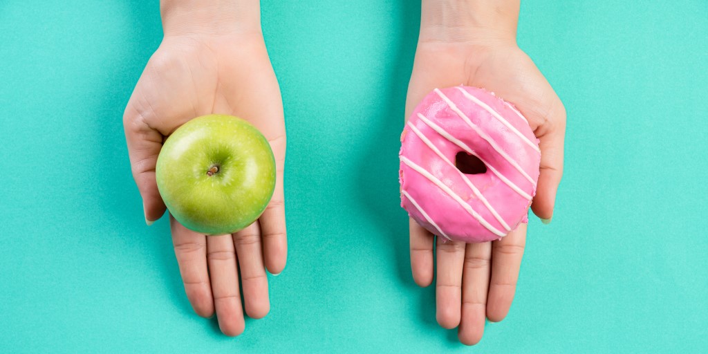 Reversing type 2 diabetes by following a low calorie diet. Image shows hands holding an apple and a donut.