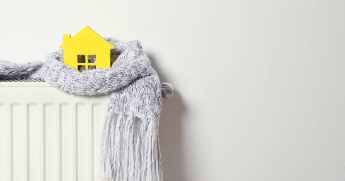 Wooden house model wrapped in scarf put on radiator