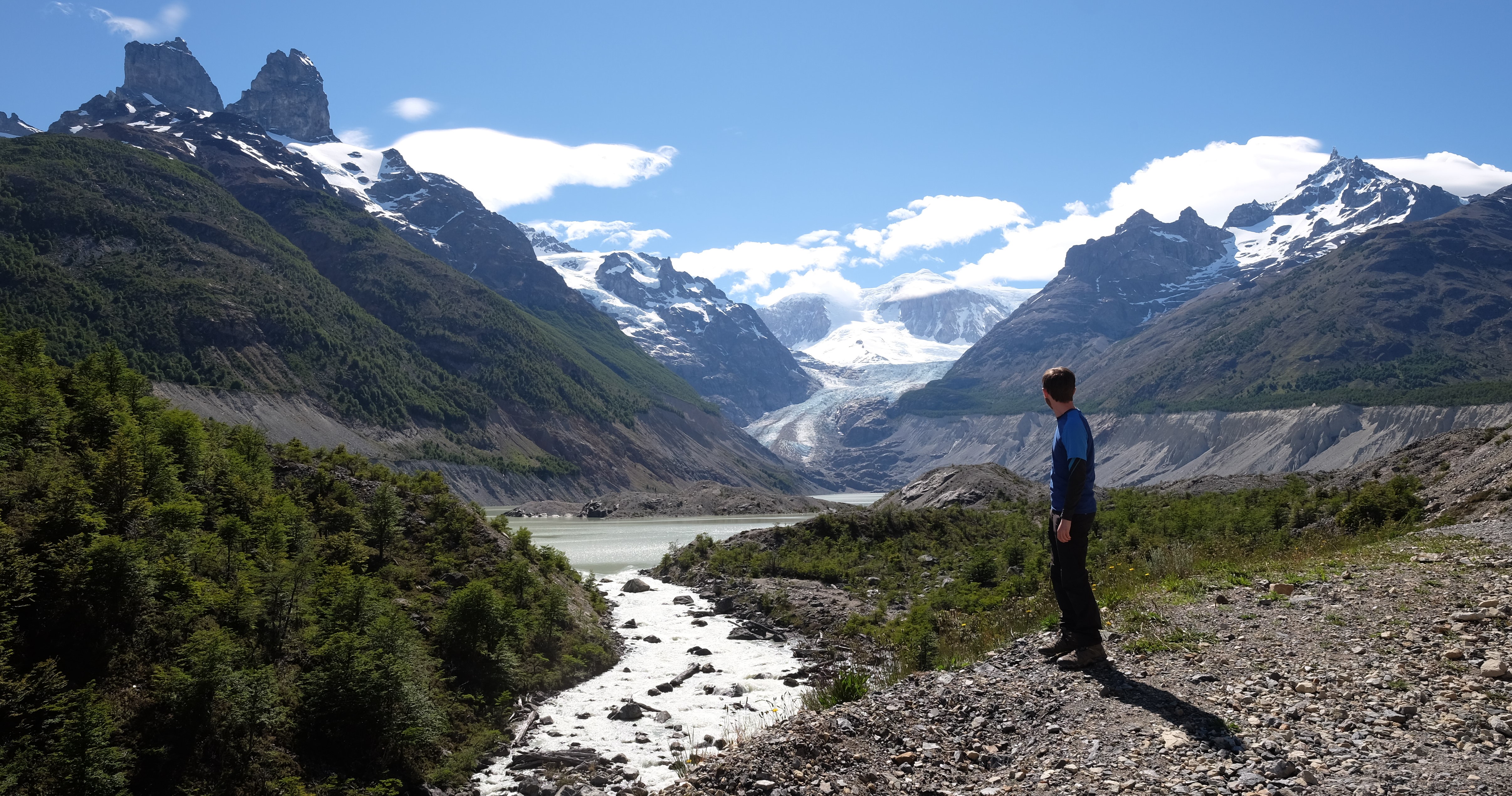 A researcher stands on a mountain, looking across at the Andes and water bodies